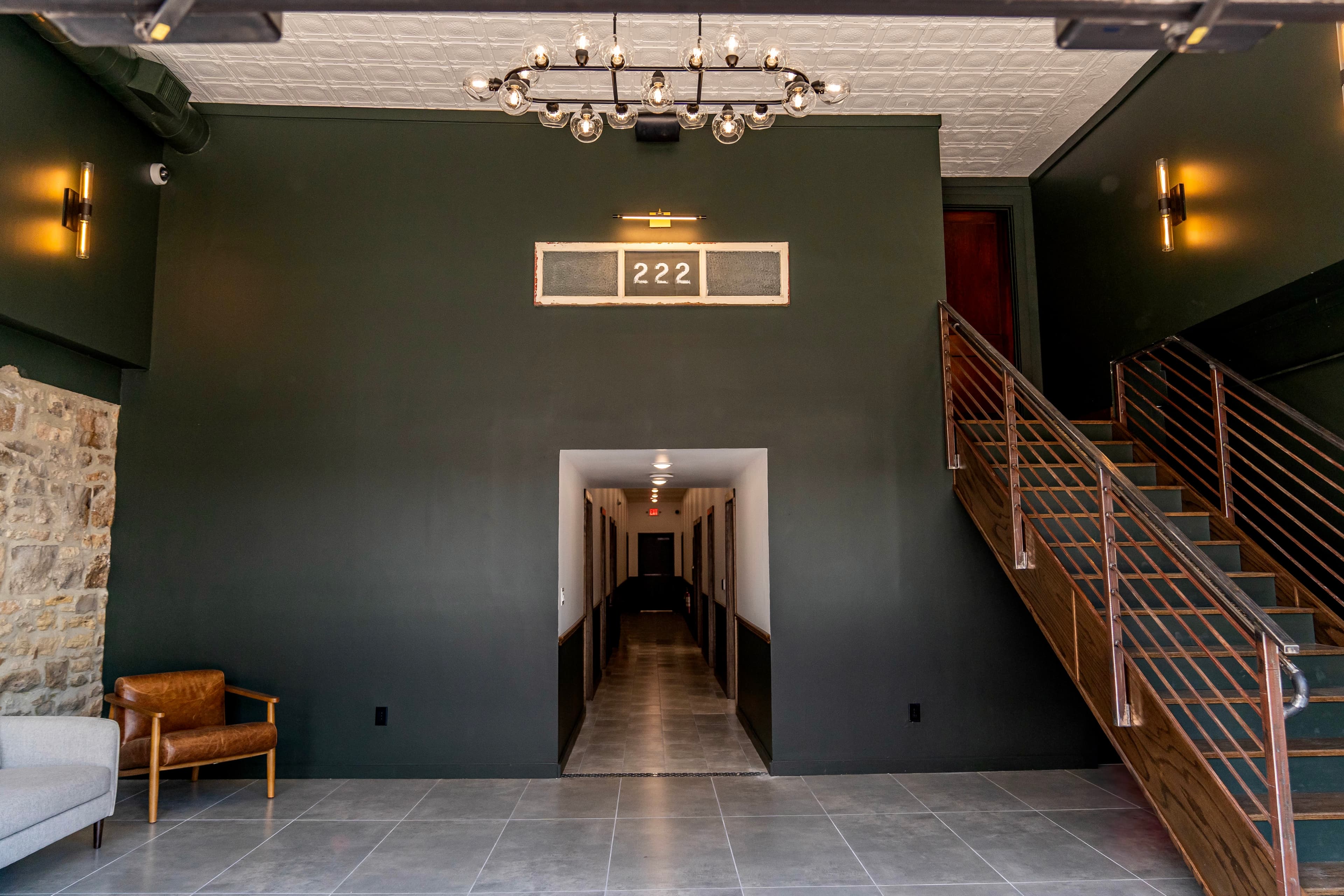 The Nest lobby with olive walls, brass lighting, and wood stair rails
