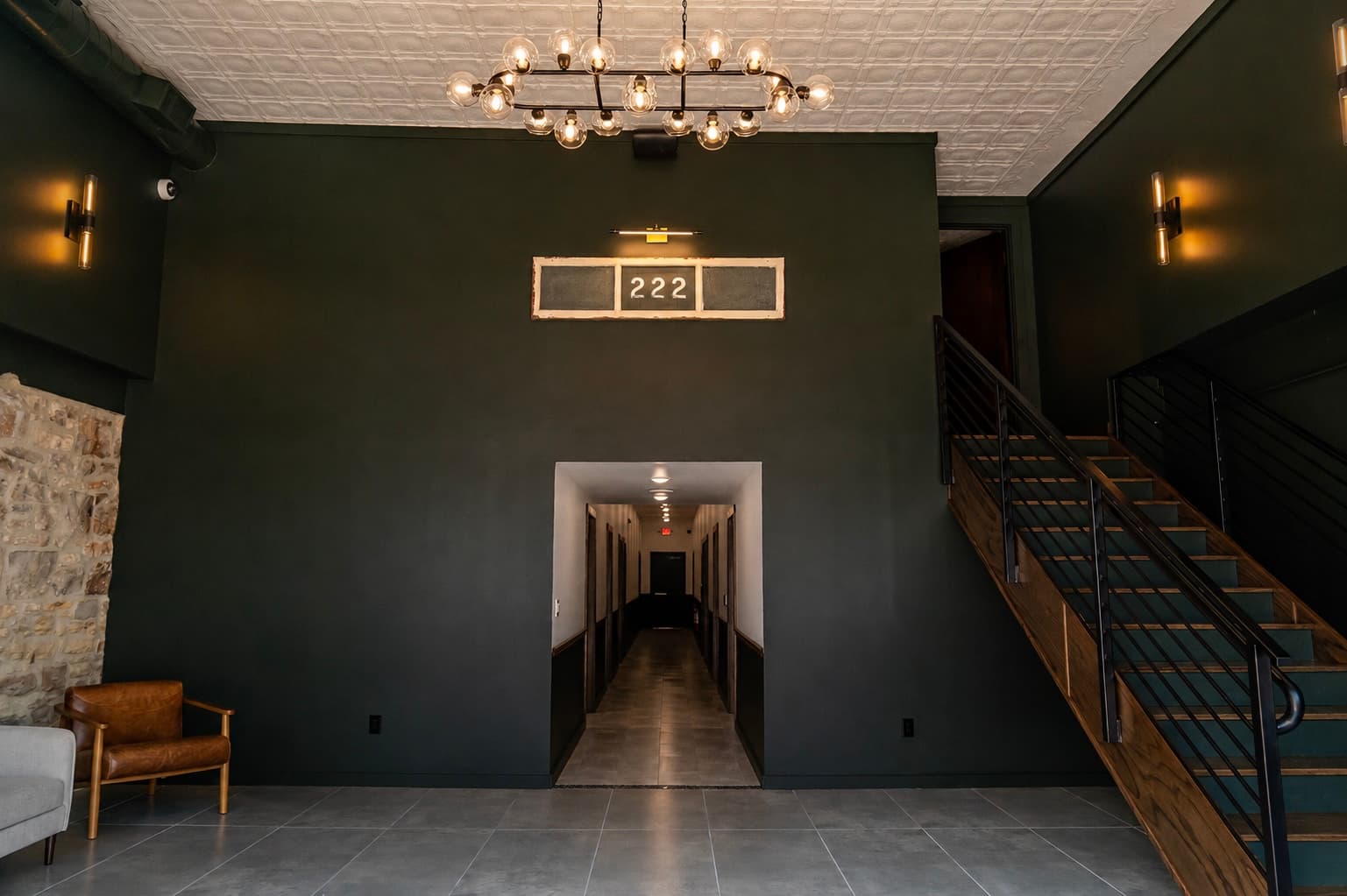 The Nest lobby with olive walls, brass lighting, and wood stair rails
